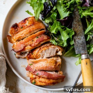 sliced bacon-wrapped chicken thigh on a plate with lettuce and a knife