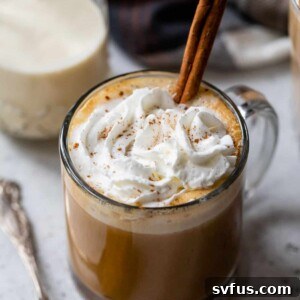pumpkin spice latte in a glass with whipped cream and a cinnamon stick