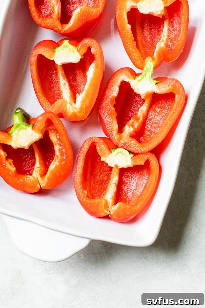 Fresh bell peppers, sliced in half and seeds removed, arranged neatly in a baking dish, ready for stuffing and baking.