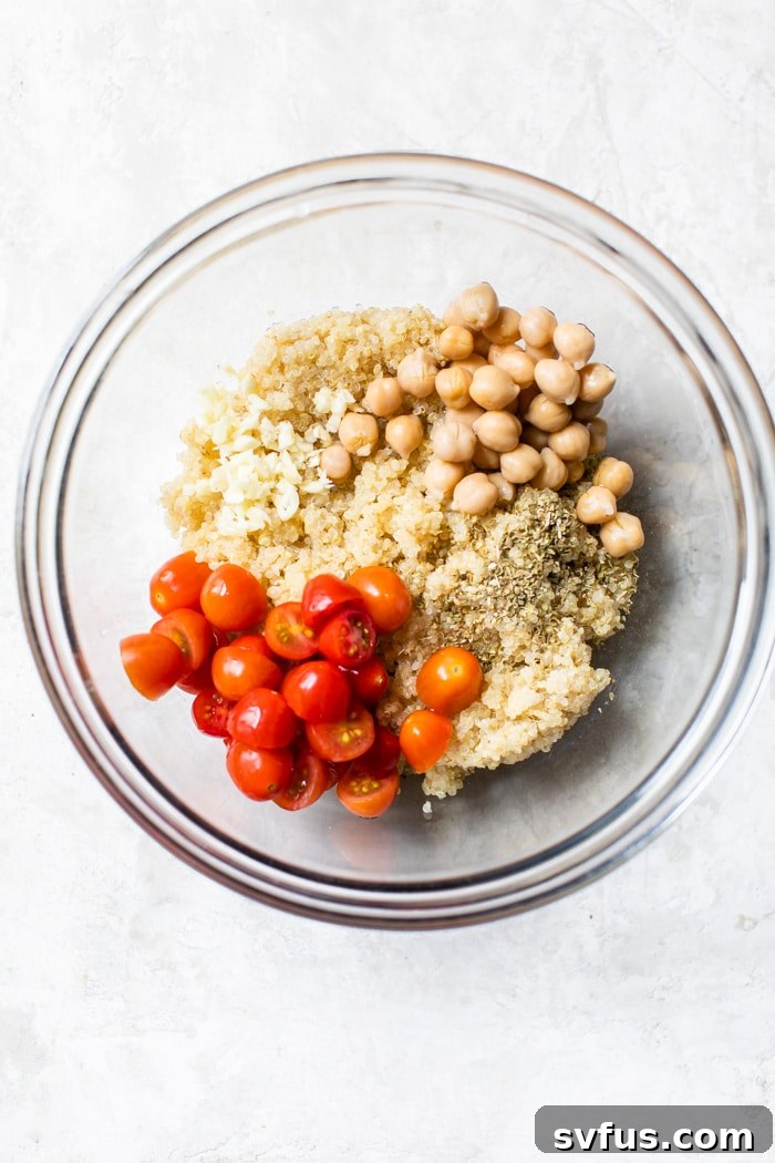 A bowl filled with cooked quinoa mixed with various vegetables like chickpeas and tomatoes, ready to be used as stuffing.