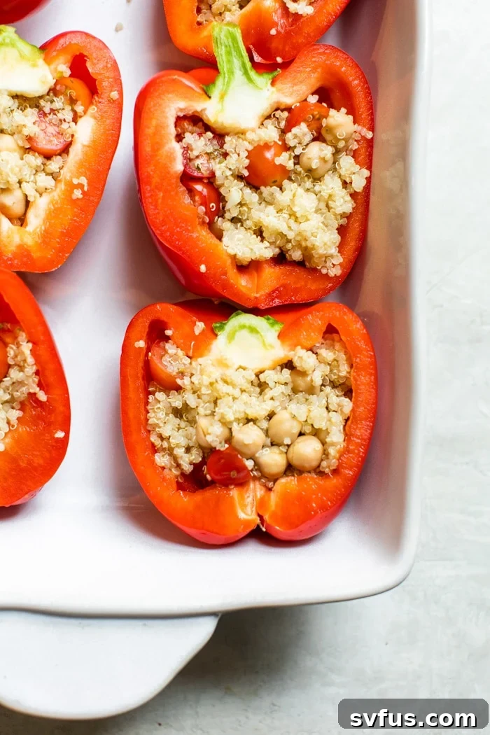 Bell peppers generously stuffed with a seasoned quinoa mixture, arranged in a baking dish, ready for baking.