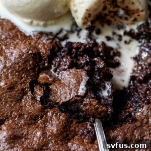 Close-up of brownie skillet with two scoops of ice cream and a spoon scooping out a bite