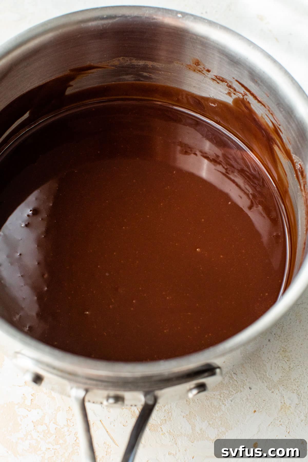 Melted butter and dark chocolate combined in a saucepan, creating a smooth, glossy mixture.