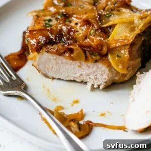 apple pork chops on a plate with a fork and with a portion of the pork chop cut off