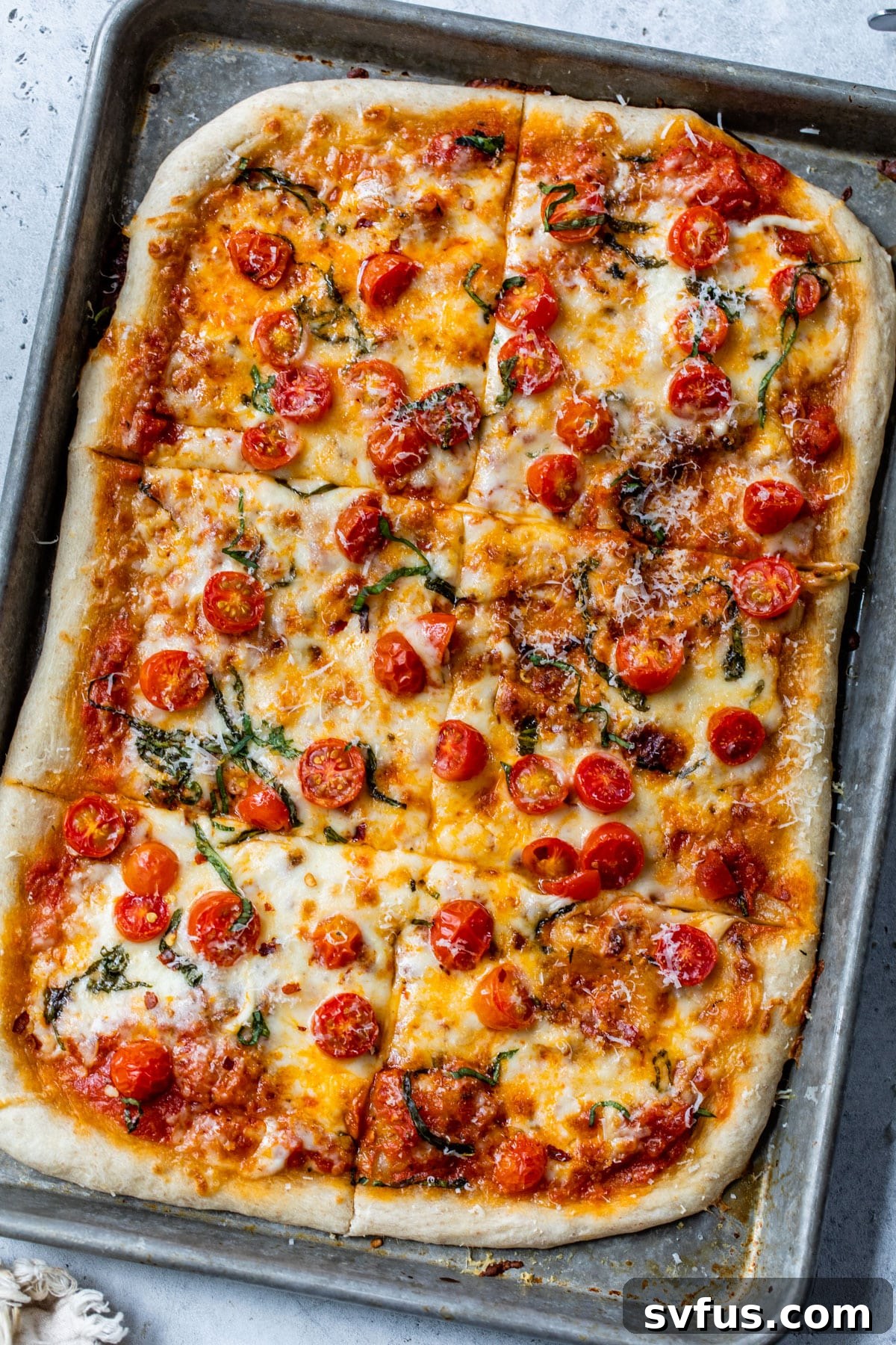 An overhead shot of a full sheet pan pizza, freshly baked and ready to be sliced.