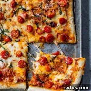 A slice of pizza being pulled away from the rest of the pizza on a baking sheet
