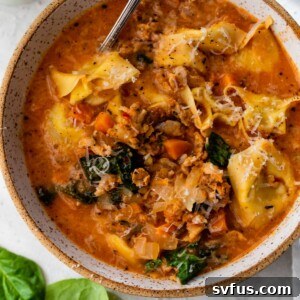 Sausage Tortellini Soup, garnished with Parmesan cheese, in a serving bowl.