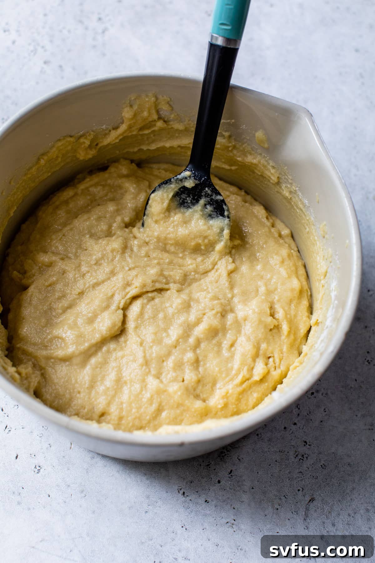 Cake batter in a large bowl with a spatula, indicating the final mixing stage before baking.