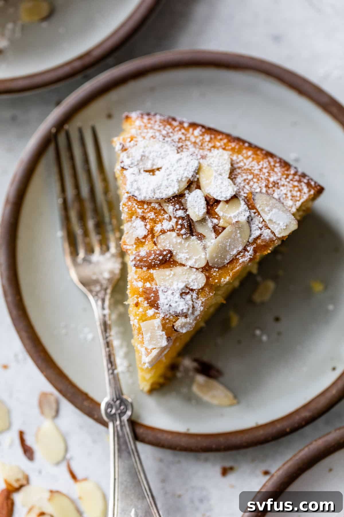 An inviting overhead view of a perfectly portioned slice of Almond Ricotta Cake on a plate, with a fork resting beside it, ready to be enjoyed.