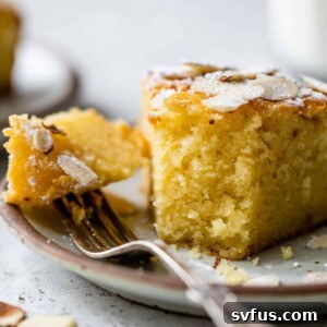 A slice of almond ricotta cake on a plate with a bite taken out with a fork