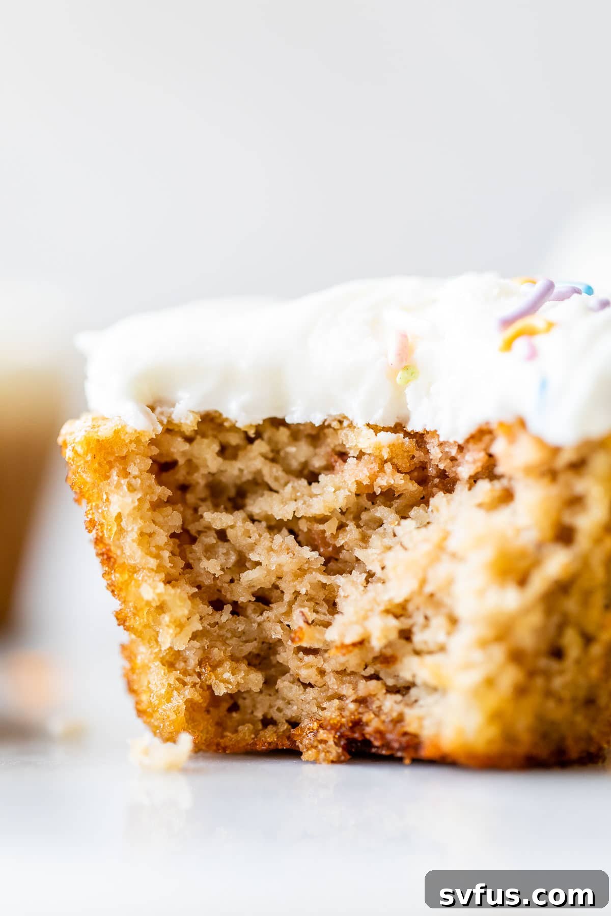 A vanilla almond flour cupcake with a bite taken out, showing its moist and tender interior.