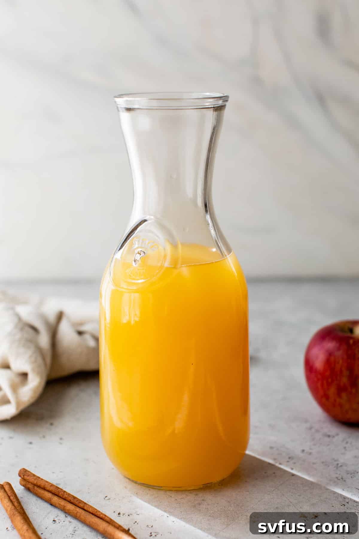 Apple cider punch expertly mixed and stored in a large glass jar, ready to chill.