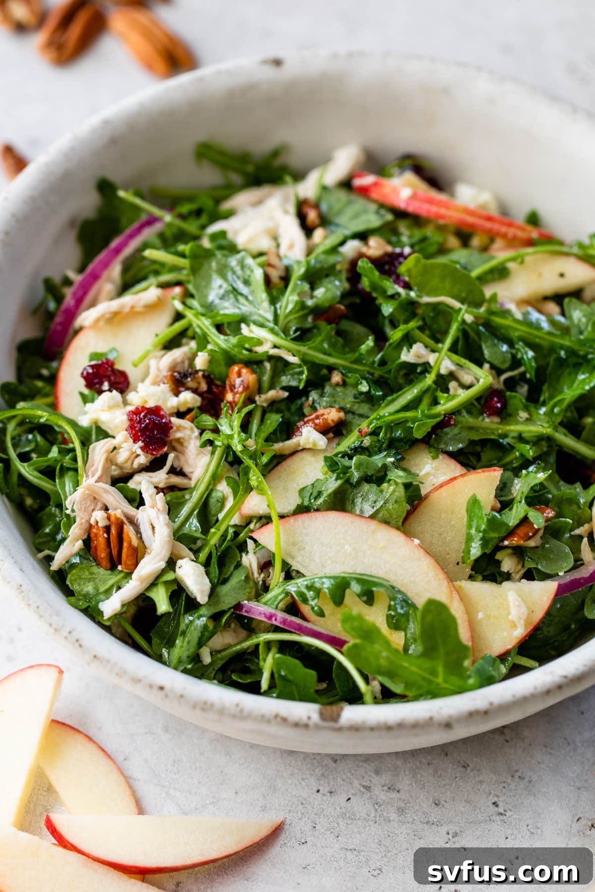 A vibrant Apple Pecan Salad fills a large ceramic bowl, ready to be served, highlighting the fresh ingredients and inviting textures.