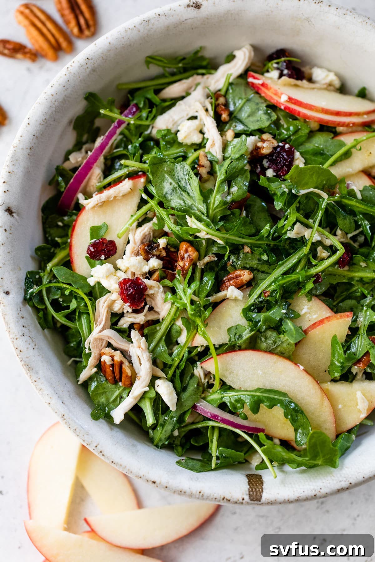 A close-up of a generous serving of Apple Pecan Salad in a bowl, highlighting its fresh ingredients and inviting colors.
