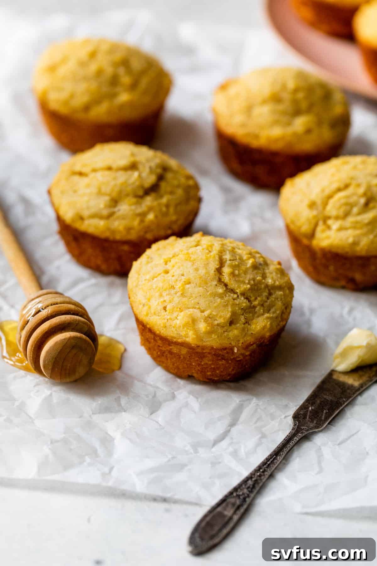 corn muffins on parchment with a knife and butter