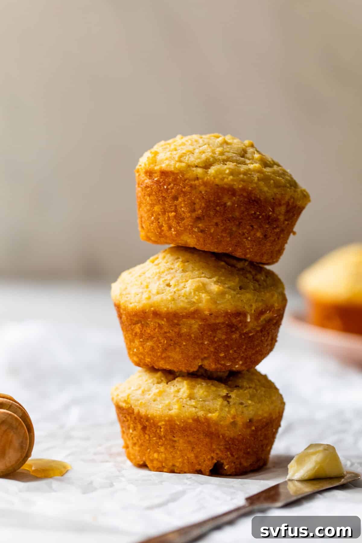 three corn muffins stacked on top of each other with a knife and butter on the side