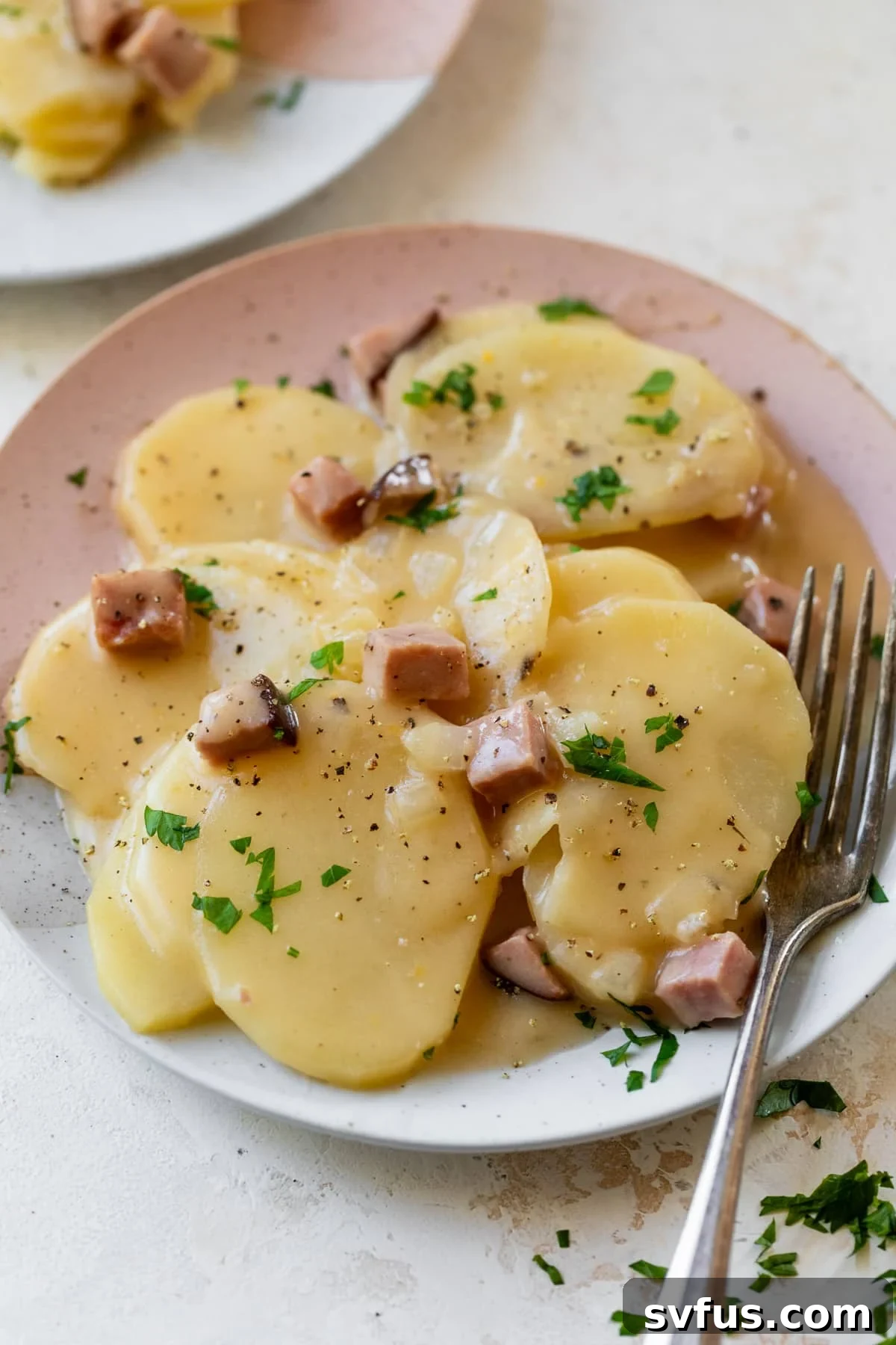 scalloped potatoes and ham on a plate with a fork, ready to be enjoyed