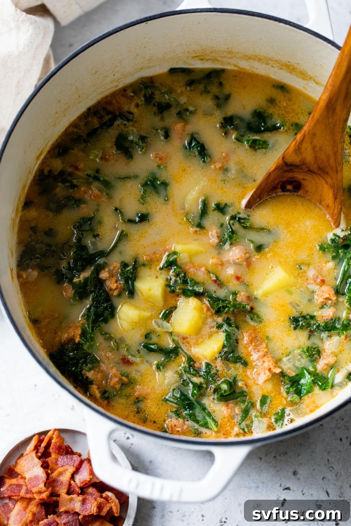 Overview of the finished Whole30 Zuppa Toscana in a Dutch oven with a wooden spoon, ready to be served.