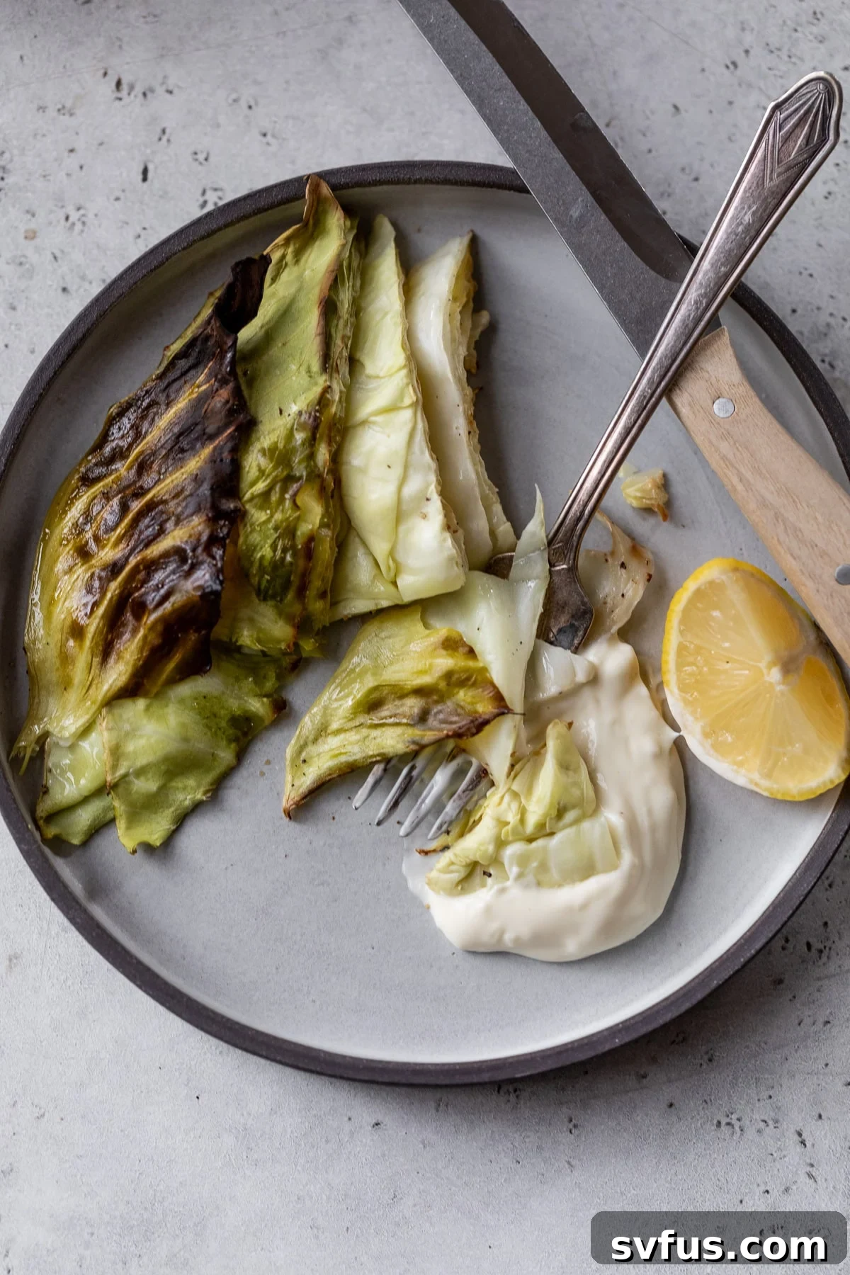 roasted cabbage wedges on a plate with sauce and a fork