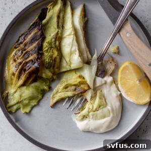 roasted cabbage wedges on a plate with sauce and a fork