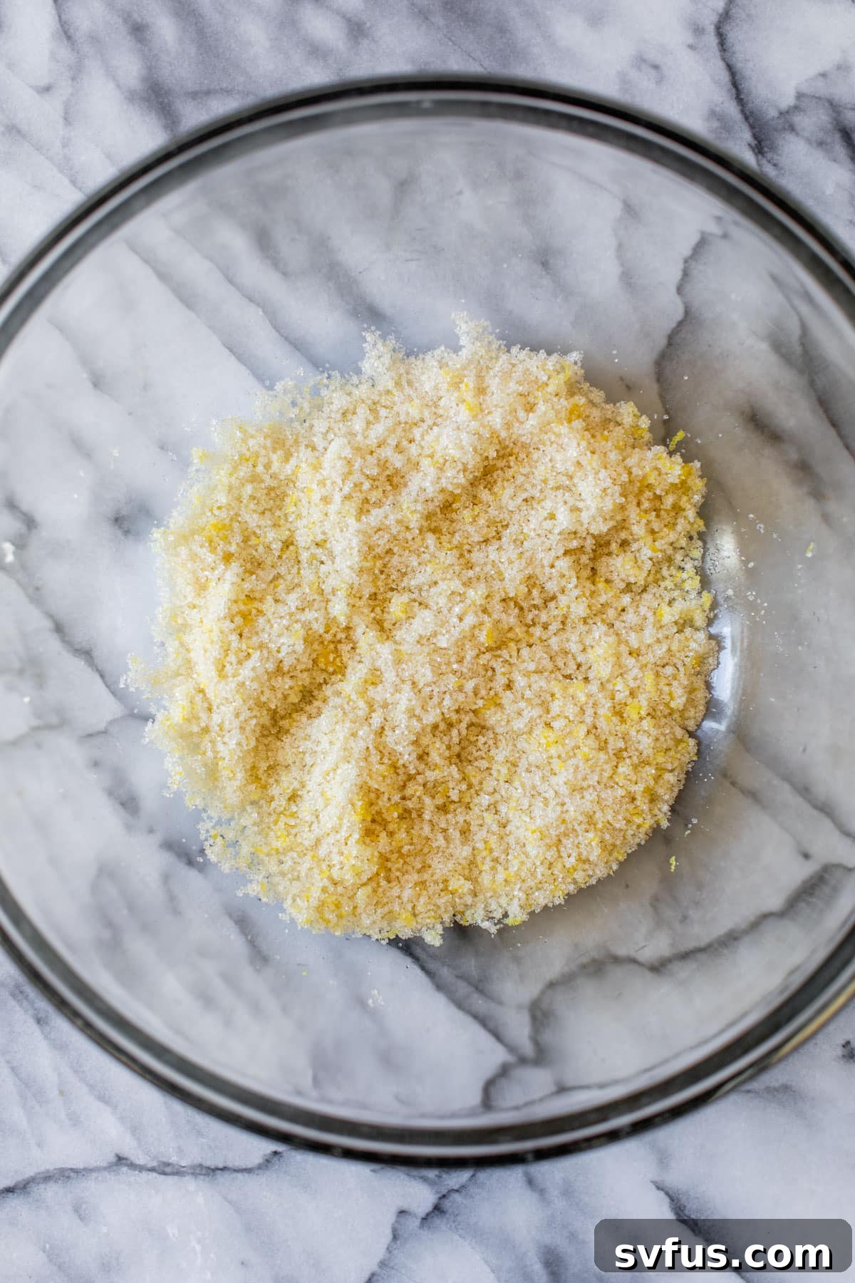 sugar and lemon zest mixed together in a glass bowl