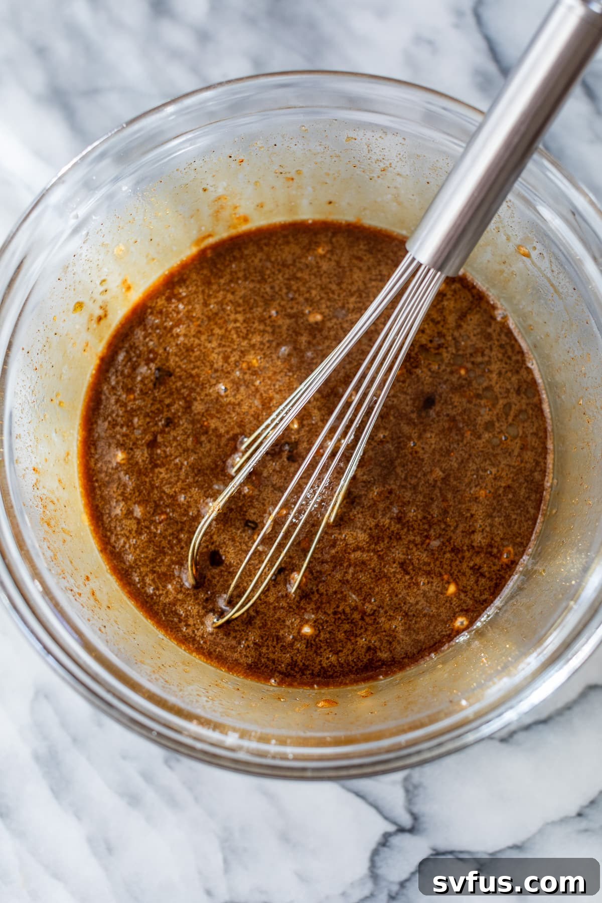 Wet ingredients for gingerbread pie filling whisked together in a clear glass bowl, ready for the next step.