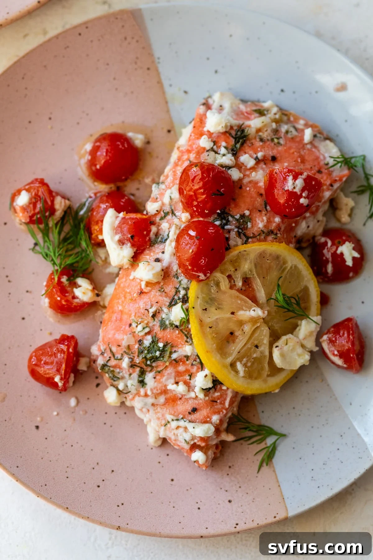Greek salmon on a plate with a lemon slice and fresh herbs