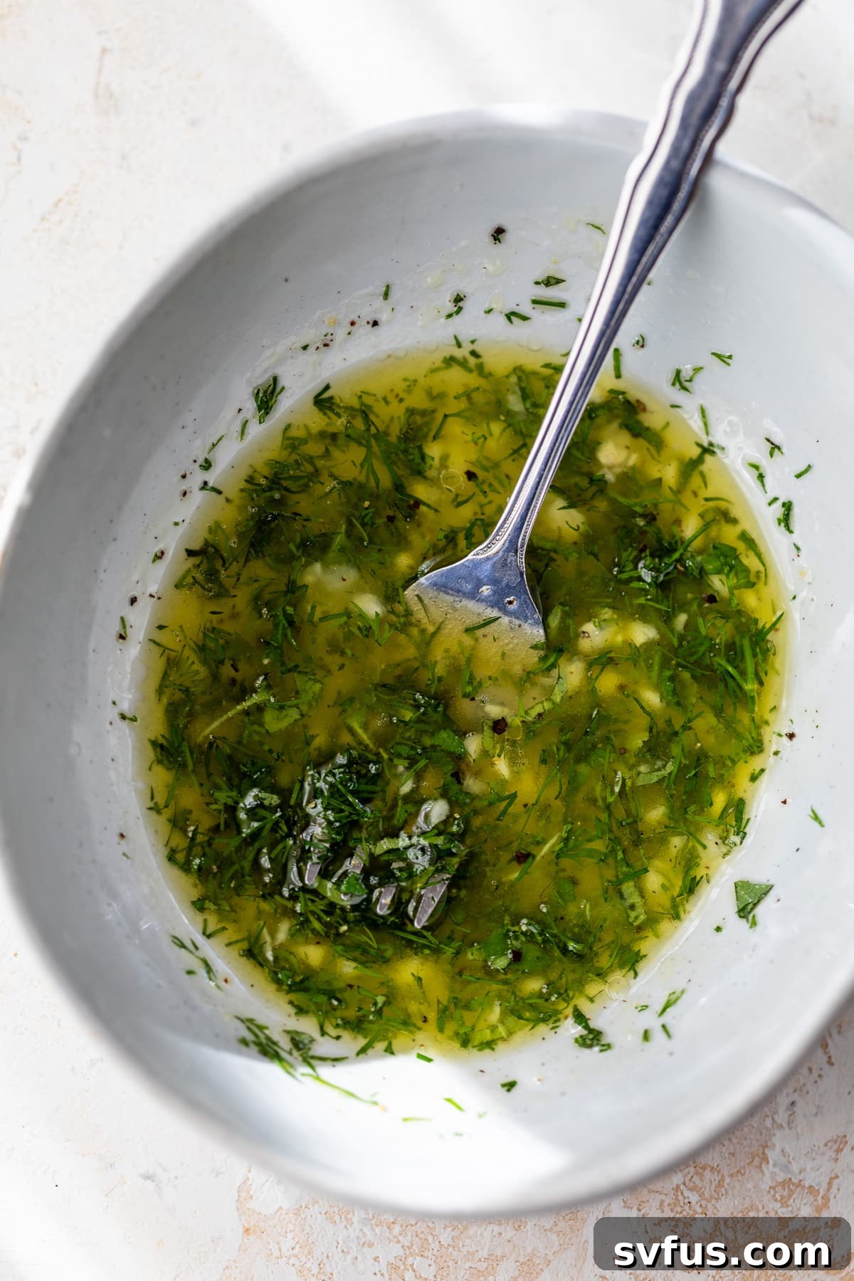 lemon juice, garlic, dill, and oregano mixed together with a fork in a small bowl