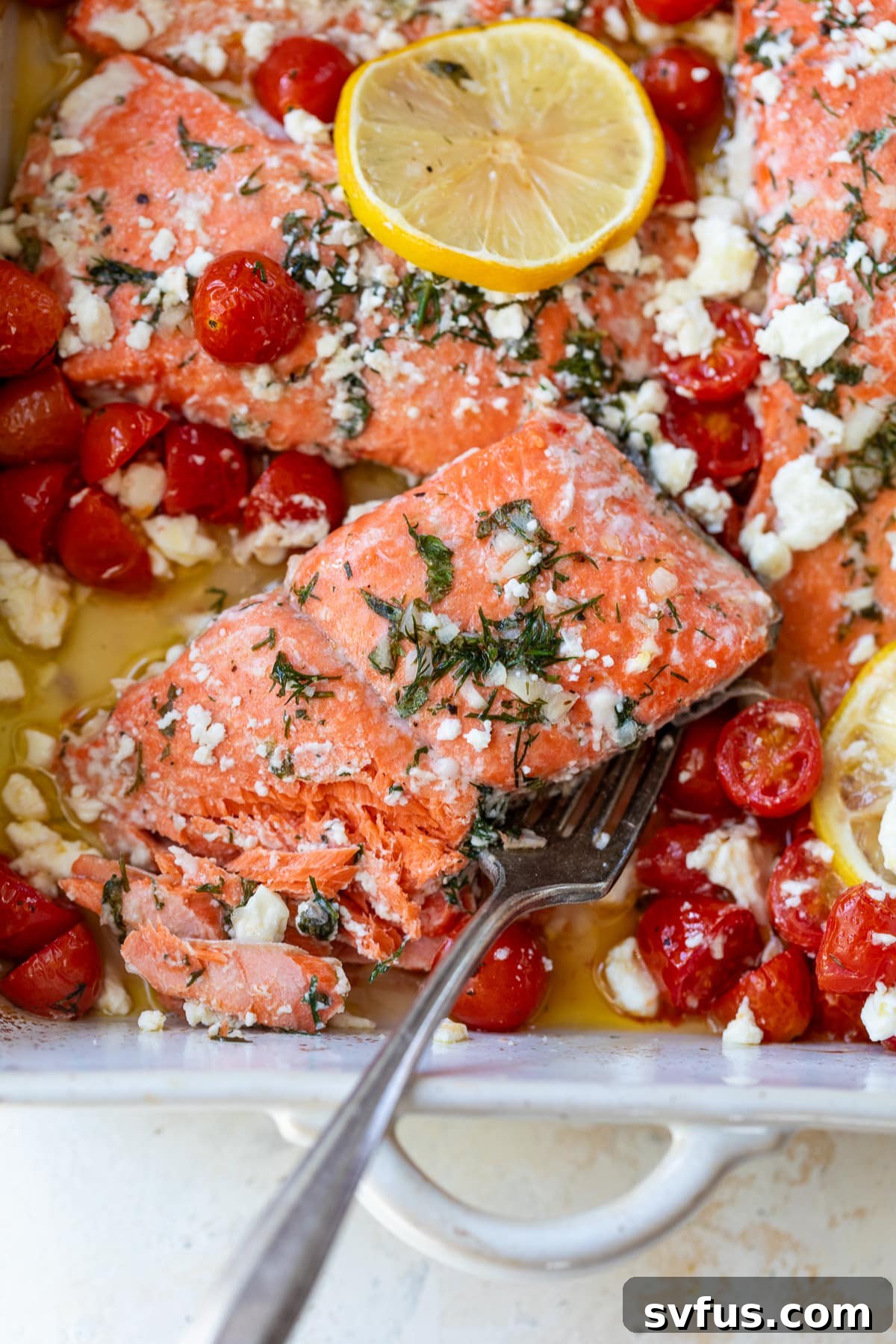 greek salmon in a baking dish with a fork