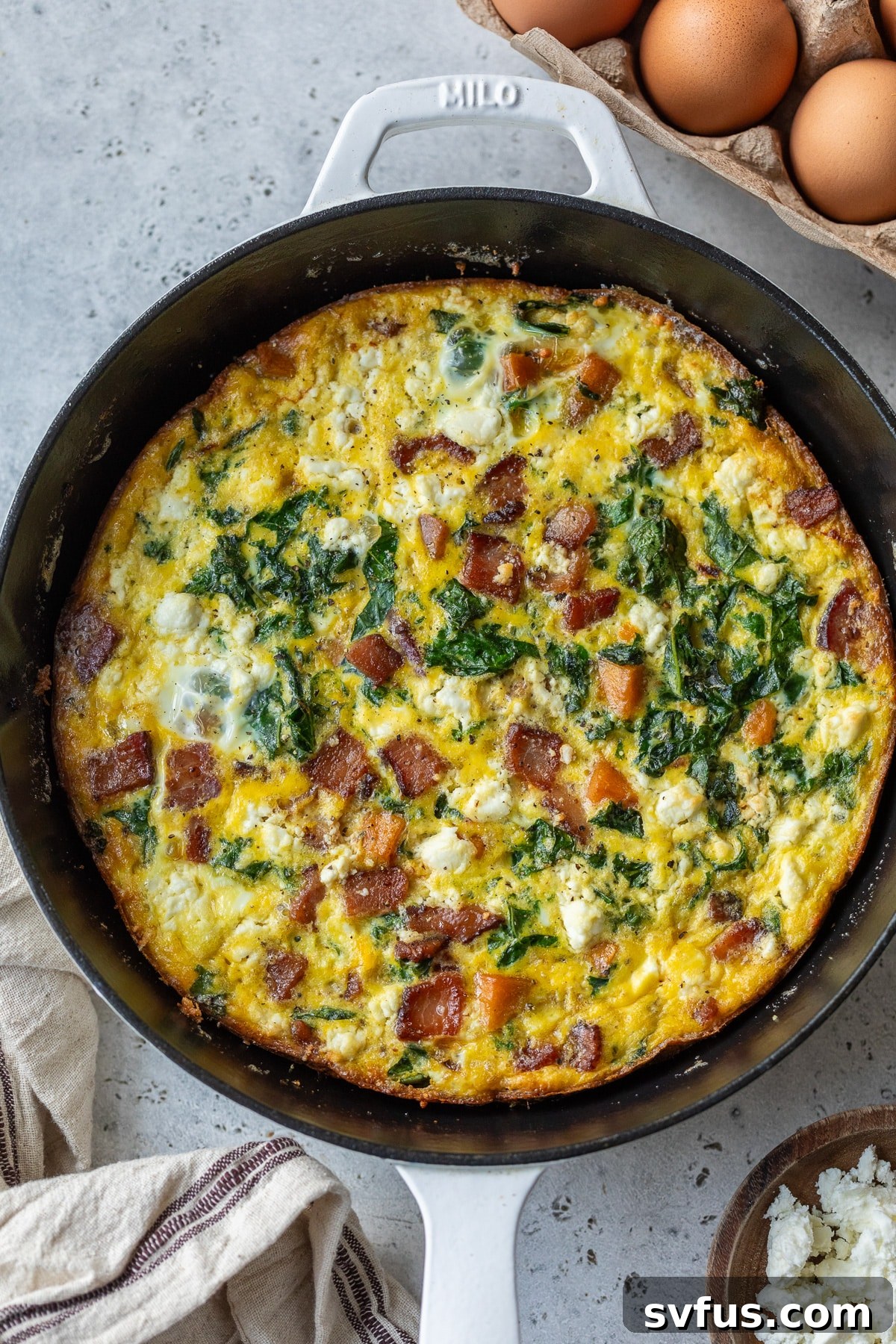 A freshly baked sweet potato frittata, golden brown and puffed, cooling in a cast iron skillet directly out of the oven.