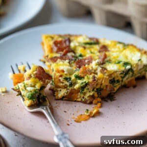 A vibrant slice of sweet potato frittata on a white plate, showing the texture and ingredients, with a bite missing.