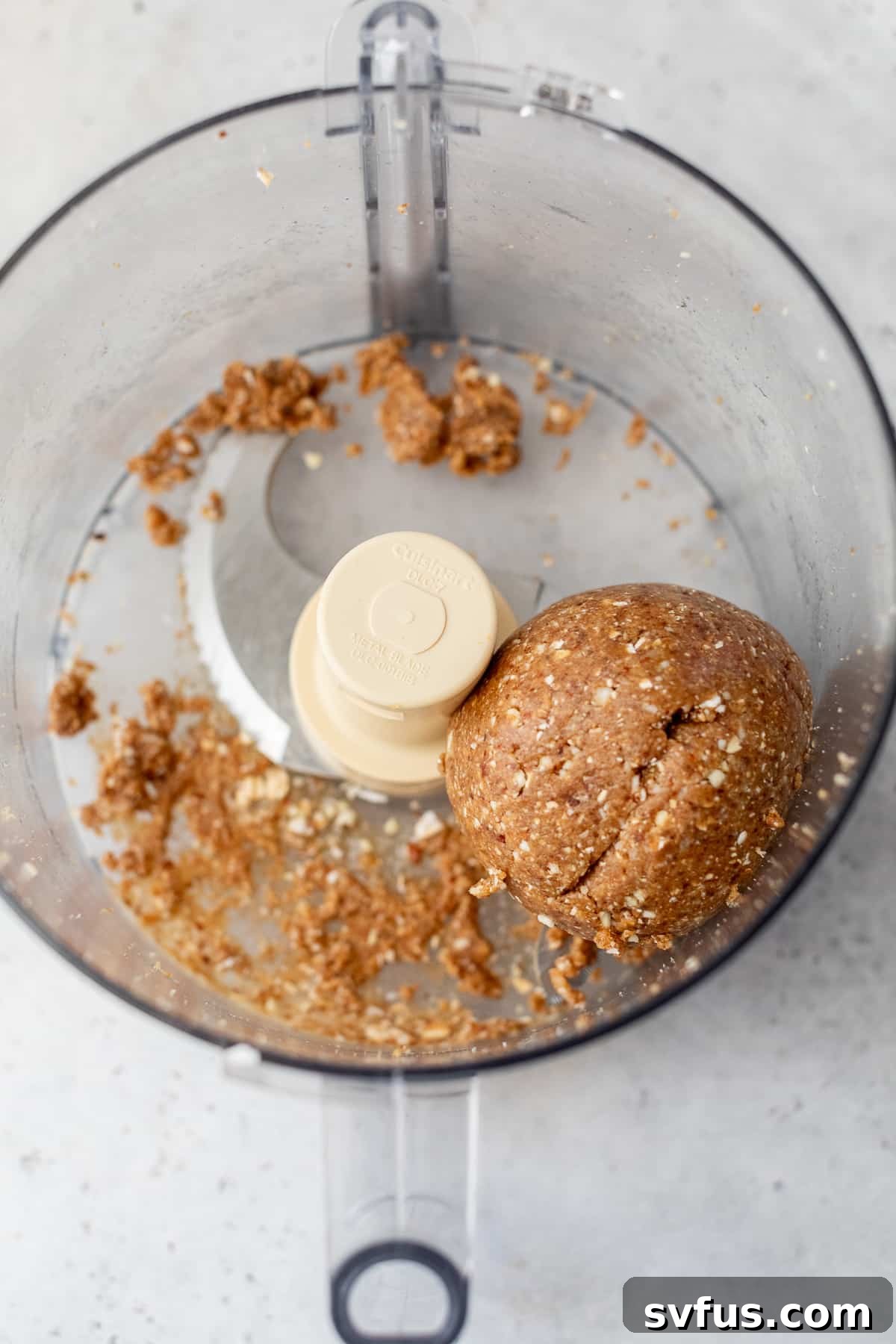 All ingredients for date energy balls are mixed thoroughly in a food processor, forming a cohesive dough.