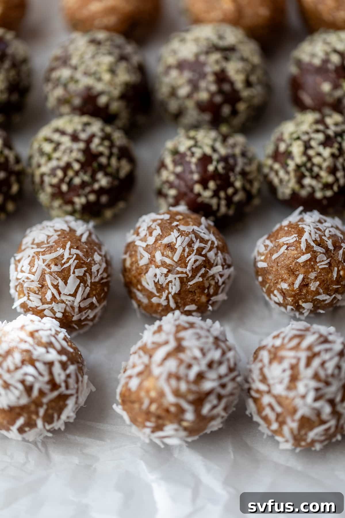 A selection of various date energy balls presented on parchment paper, ready for storage.