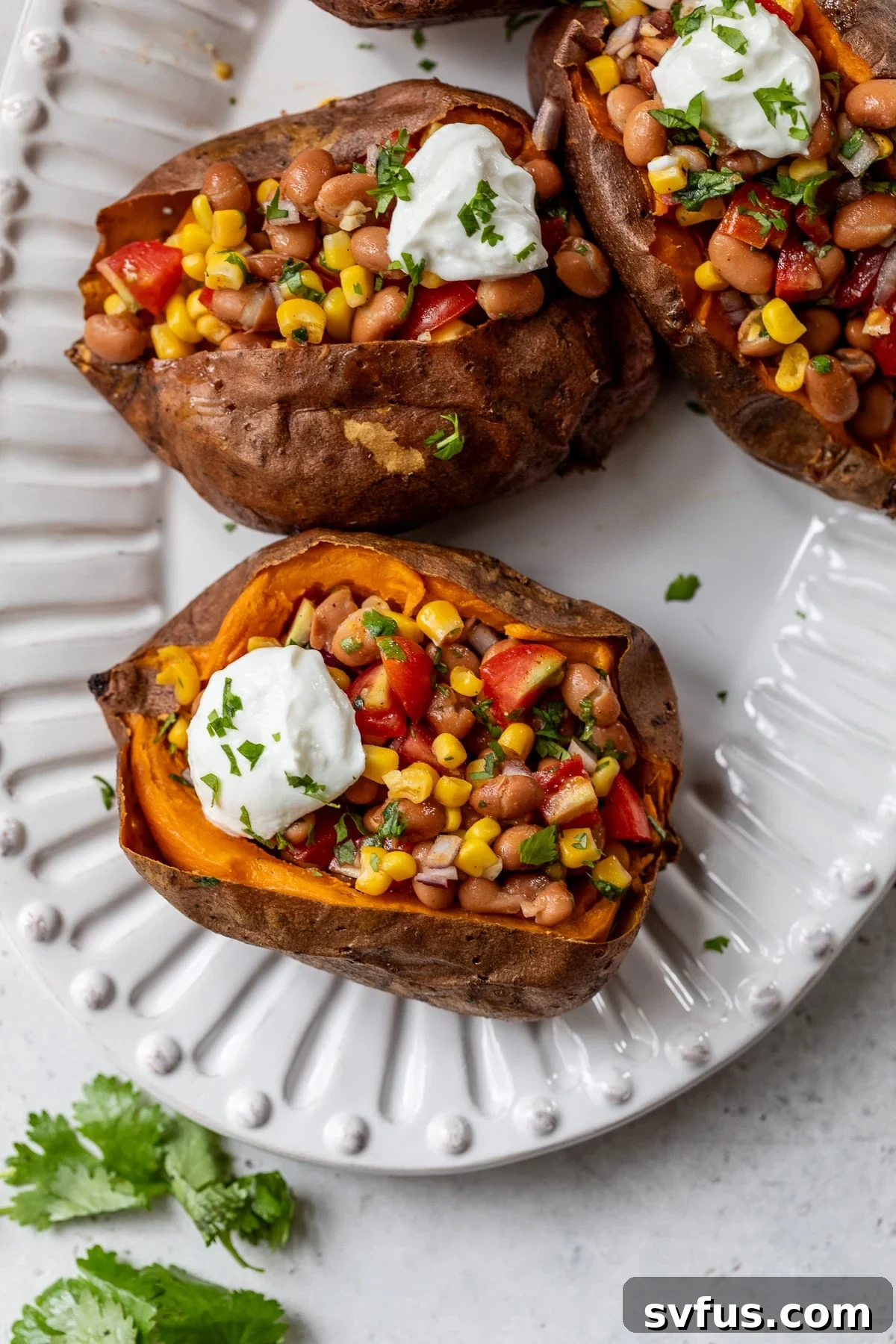vegan stuffed sweet potatoes on a plate topped with sour cream