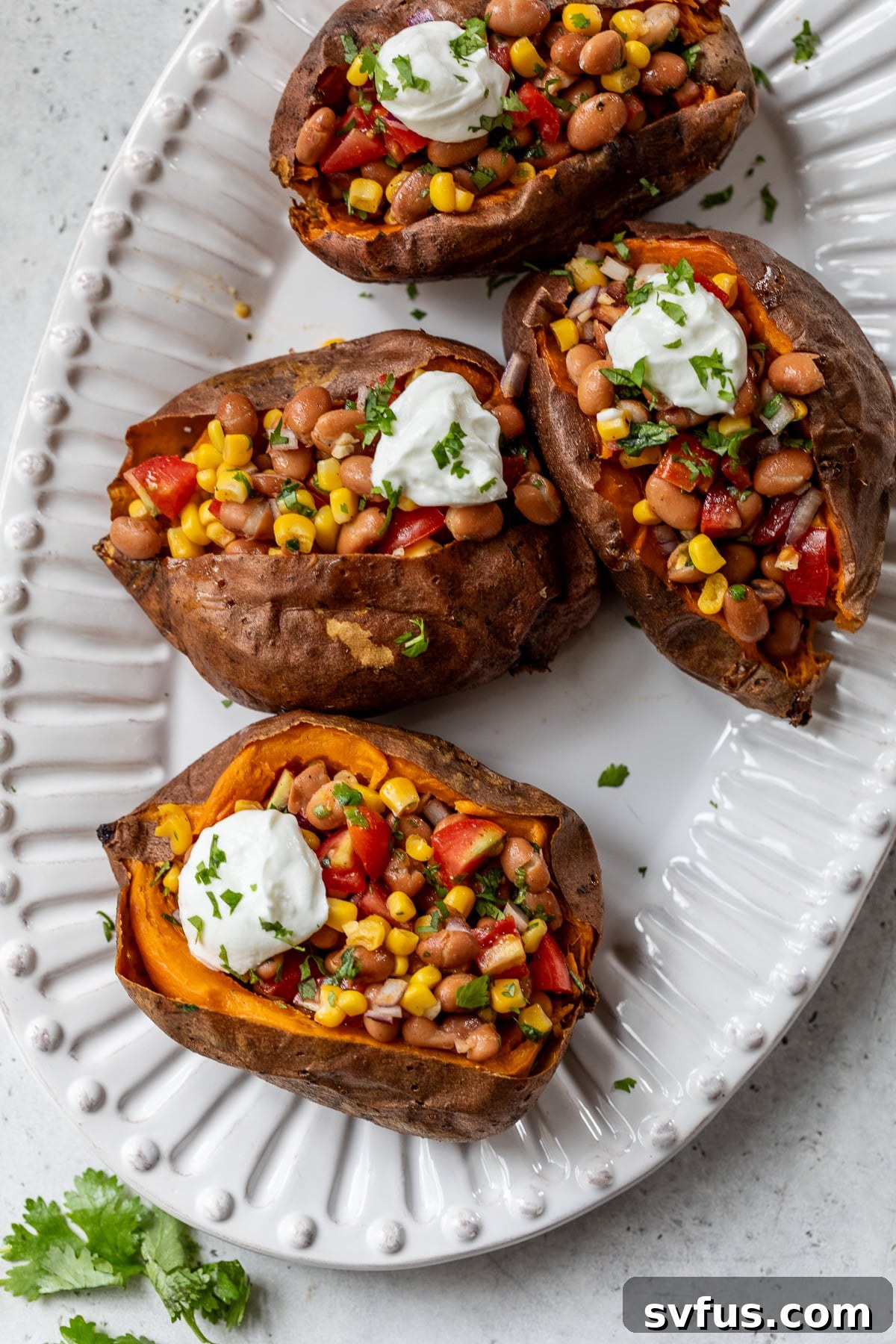 vegan stuffed sweet potatoes on a plate topped with sour cream