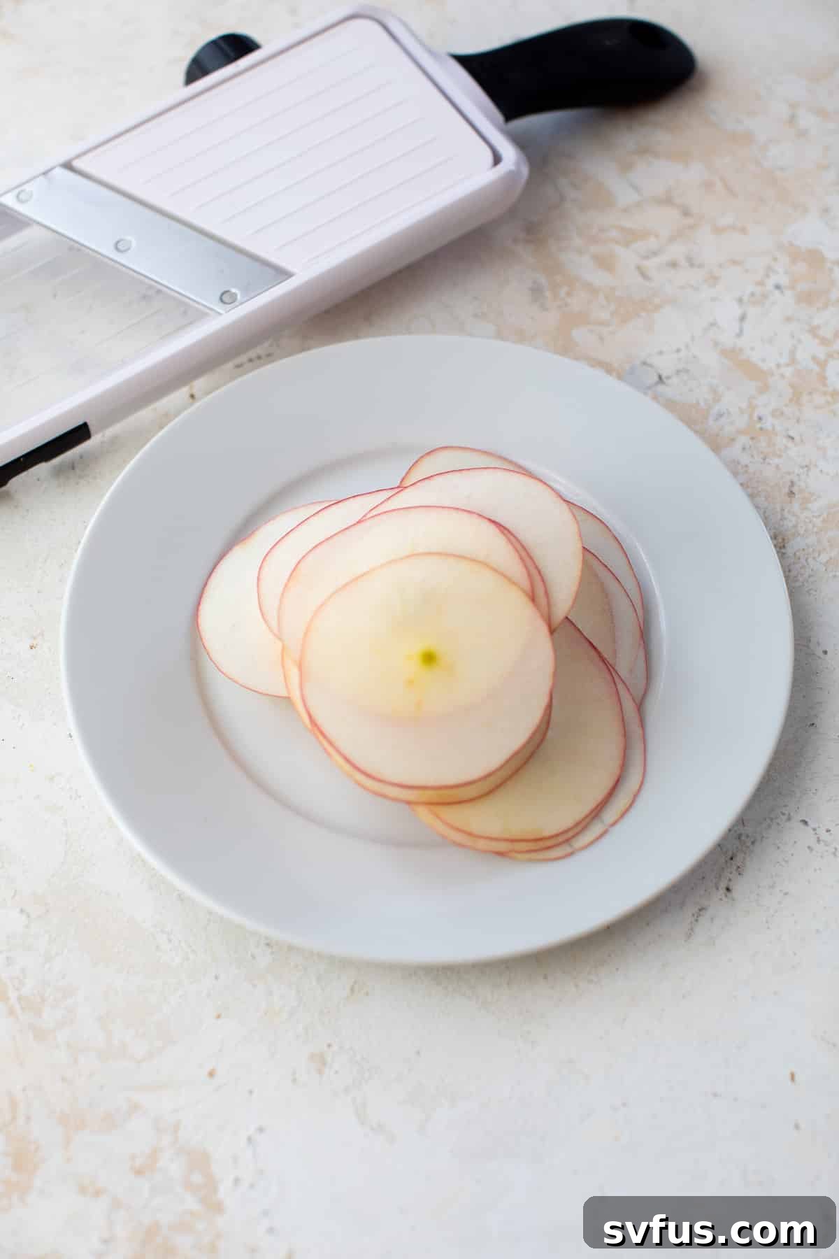 Thinly sliced apple rounds arranged on a white plate, ready for seasoning.