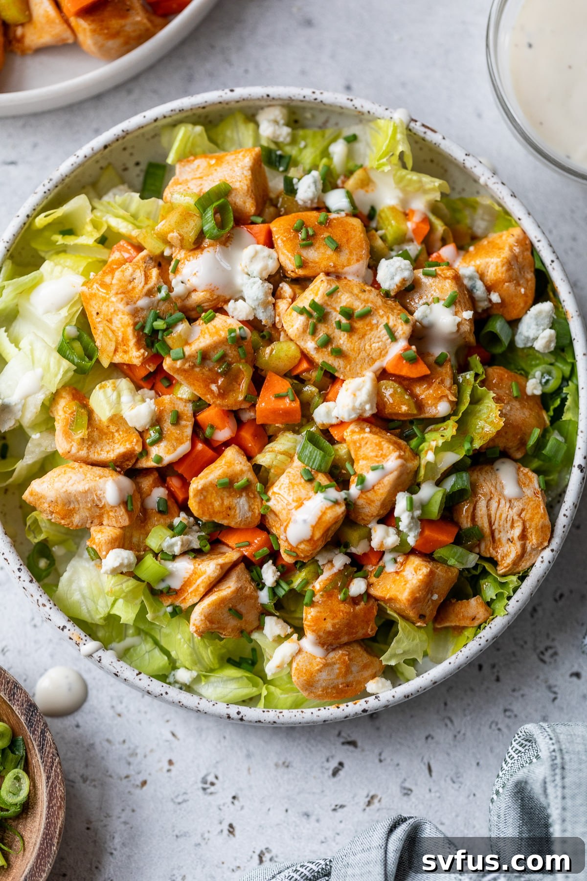 A fully assembled bowl of Buffalo Chicken Salad with dressing and garnishes