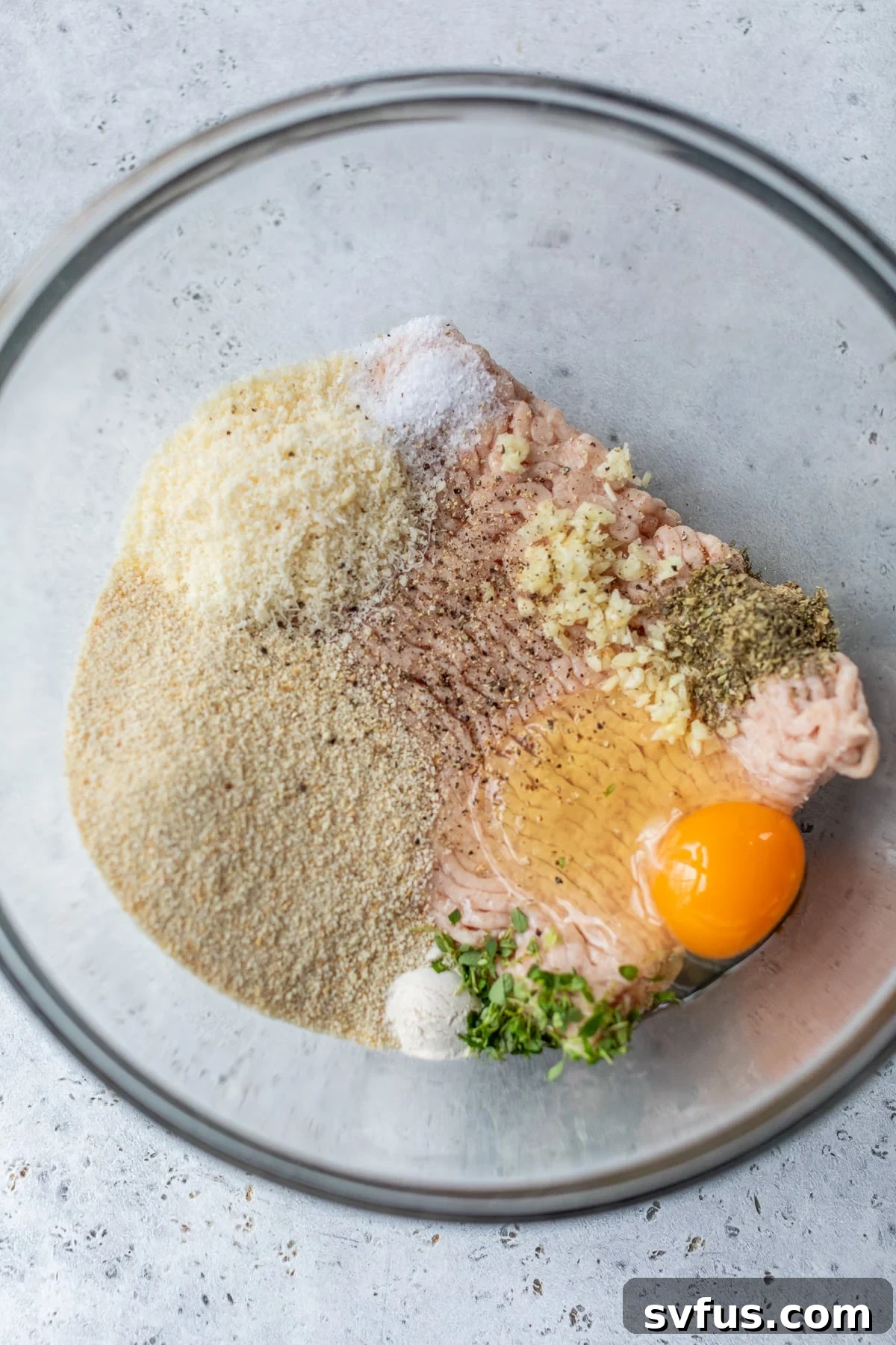 all ingredients for the meatballs added to a glass bowl