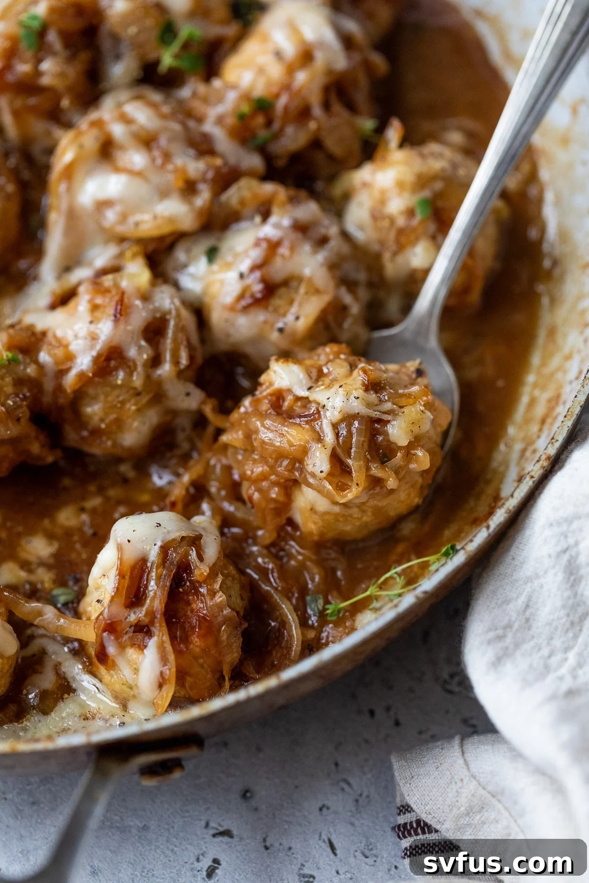 french onion chicken meatballs in a skillet with a spoon