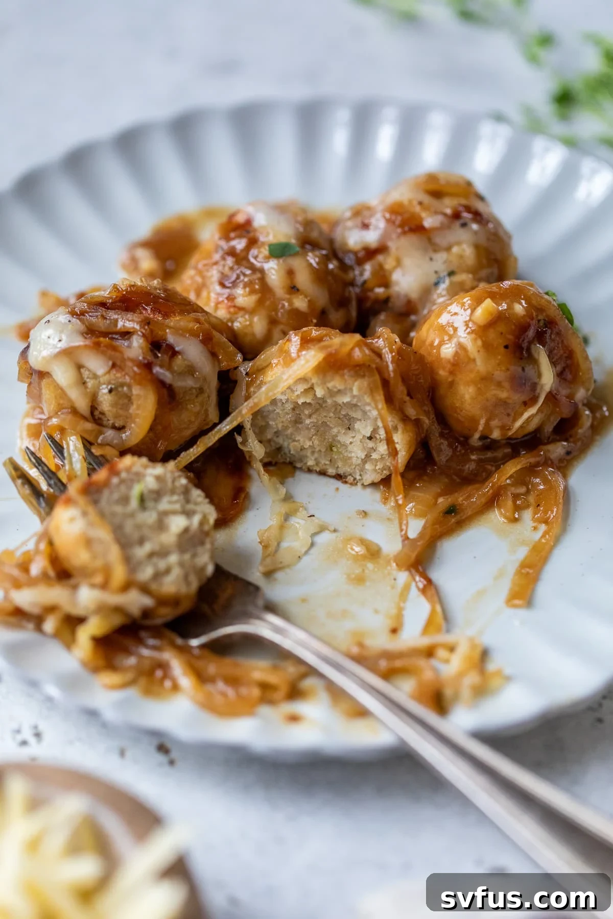 french onion chicken meatballs on a plate with a fork and a bite taken out of one meatball