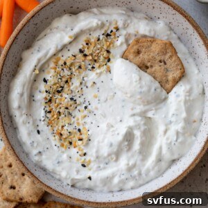 everything bagel dip in a bowl with a cracker and carrots off to the side