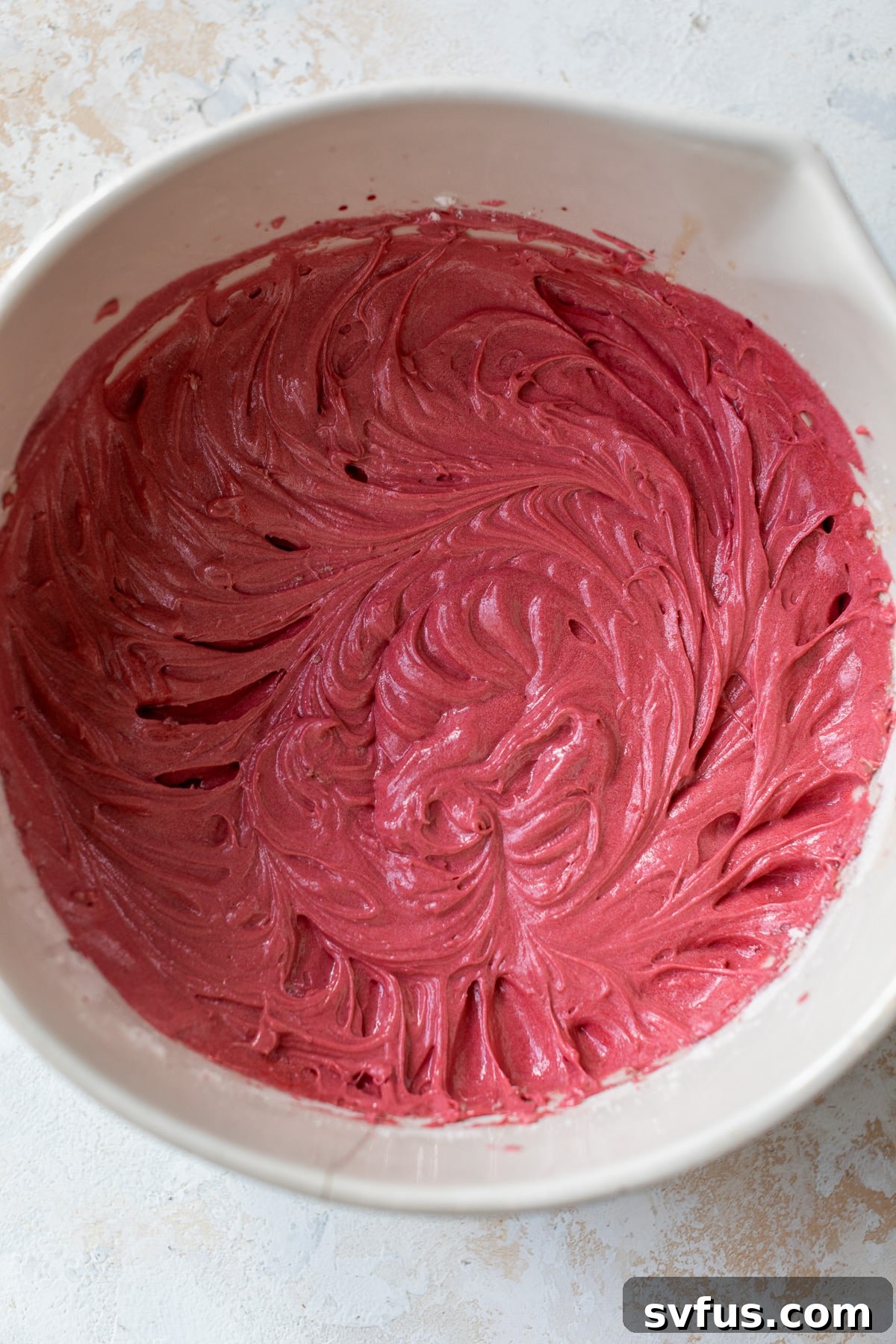 A large bowl filled with vibrant red velvet cupcake batter, perfectly mixed and ready for baking.