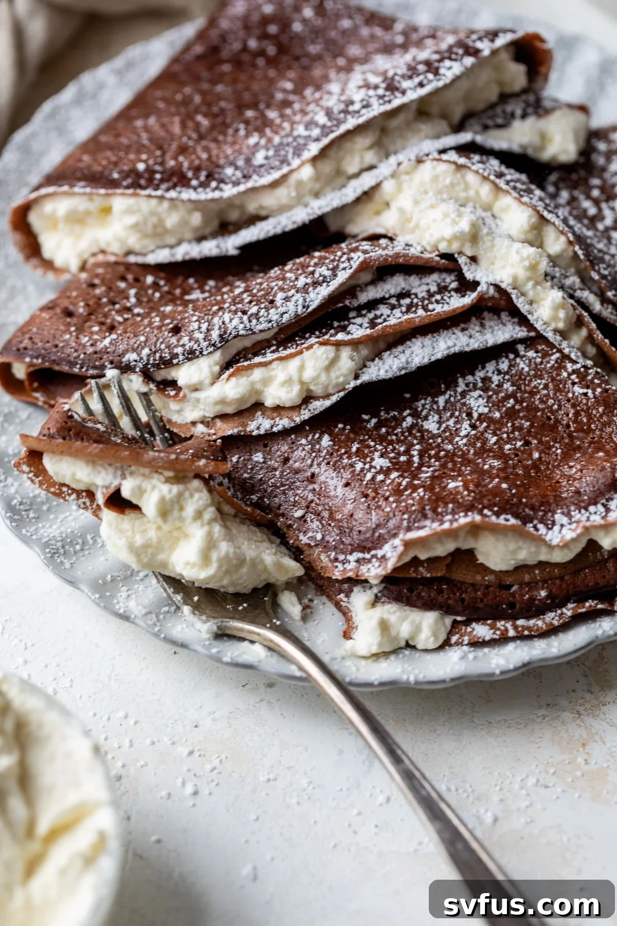 chocolate crepes stuffed with whipped cream on a plate with a fork, ready to be enjoyed for breakfast or brunch