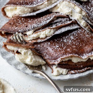 chocolate crepes stuffed with whipped cream on a plate with a fork