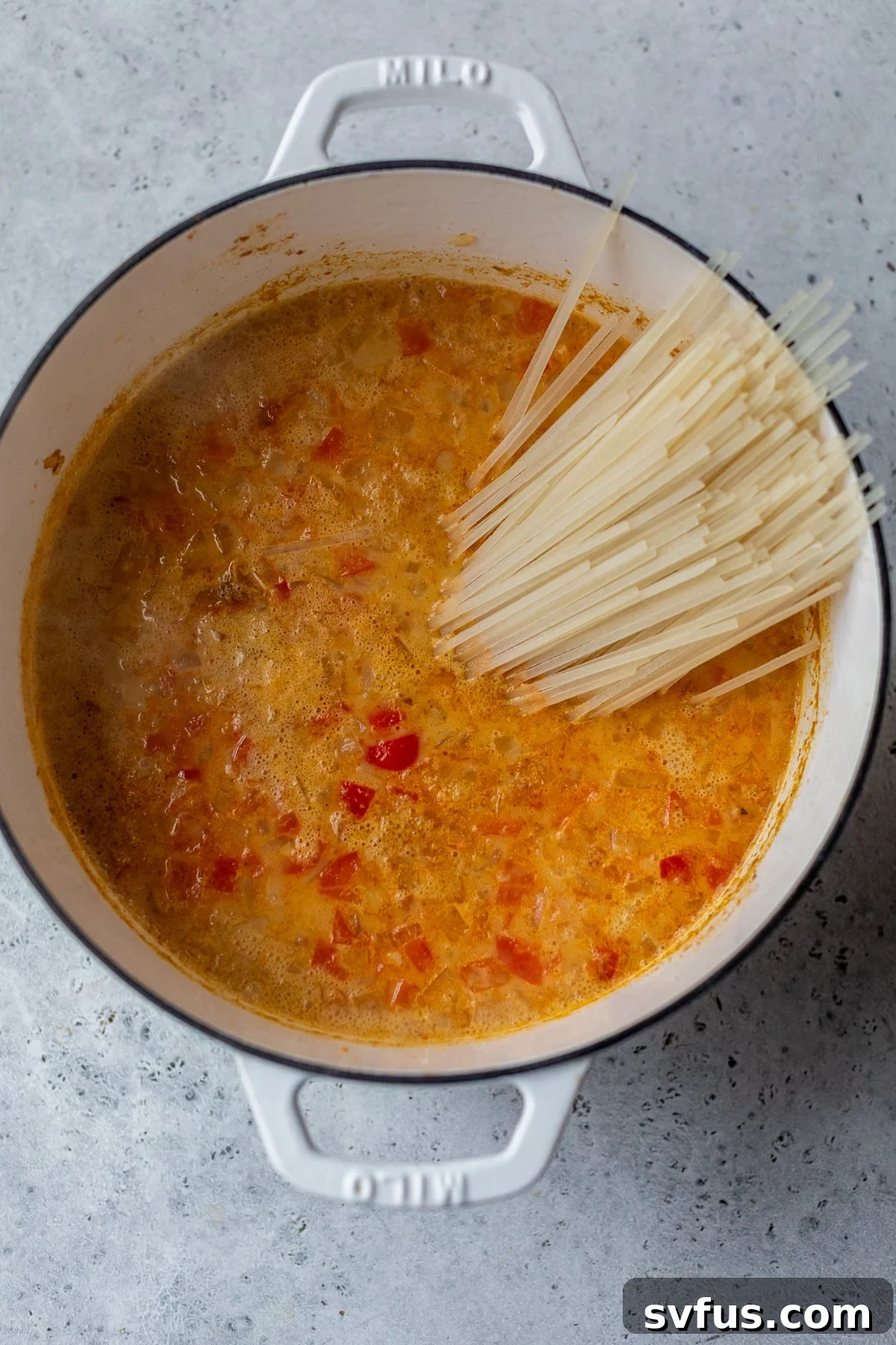 rice noodles added to the dutch oven with vegetables, broth, and coconut milk