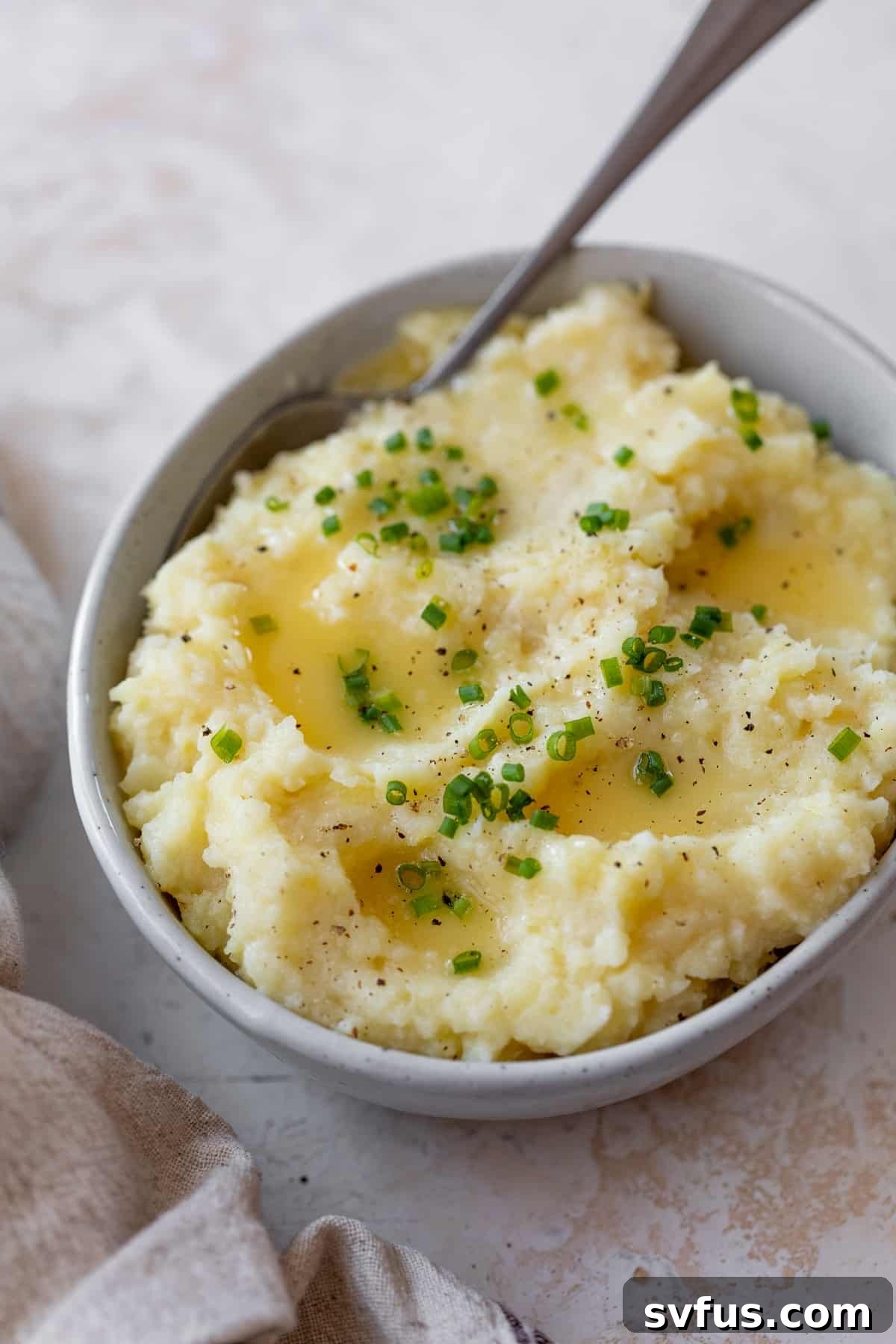 A bowl of creamy mashed parsnips with a spoon resting in it, ready to be served.
