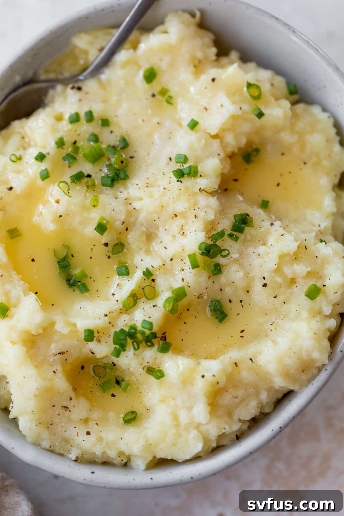 Close-up of creamy mashed parsnips in a bowl with a spoon, showing the rich texture.