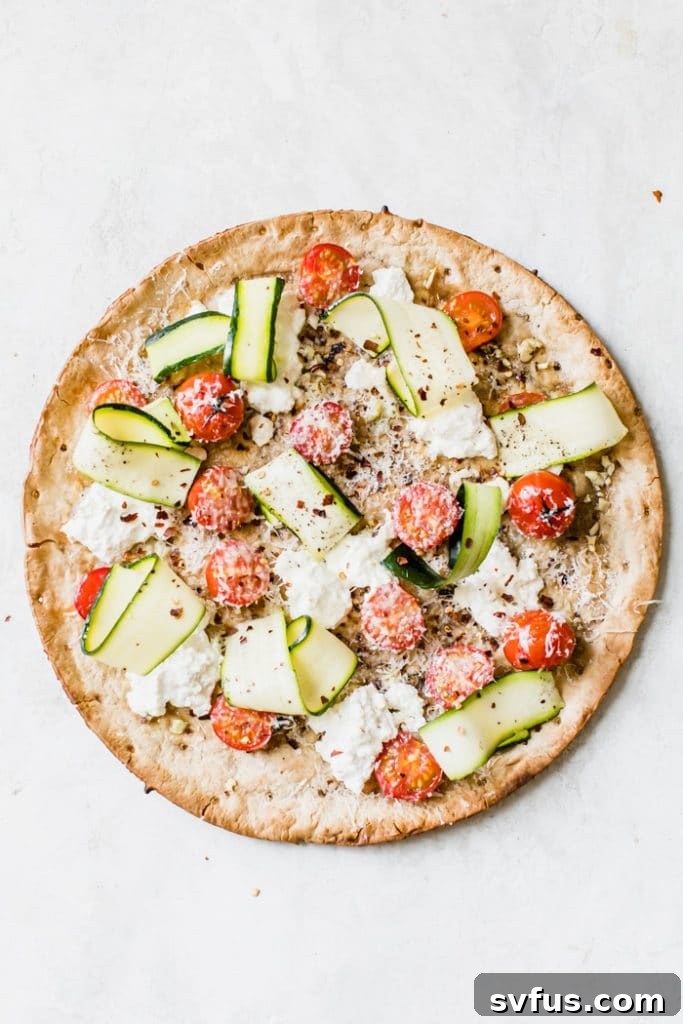 Close-up of Weeknight Veggie Pizza, perfectly baked with melted cheese, fresh zucchini ribbons, and vibrant tomatoes
