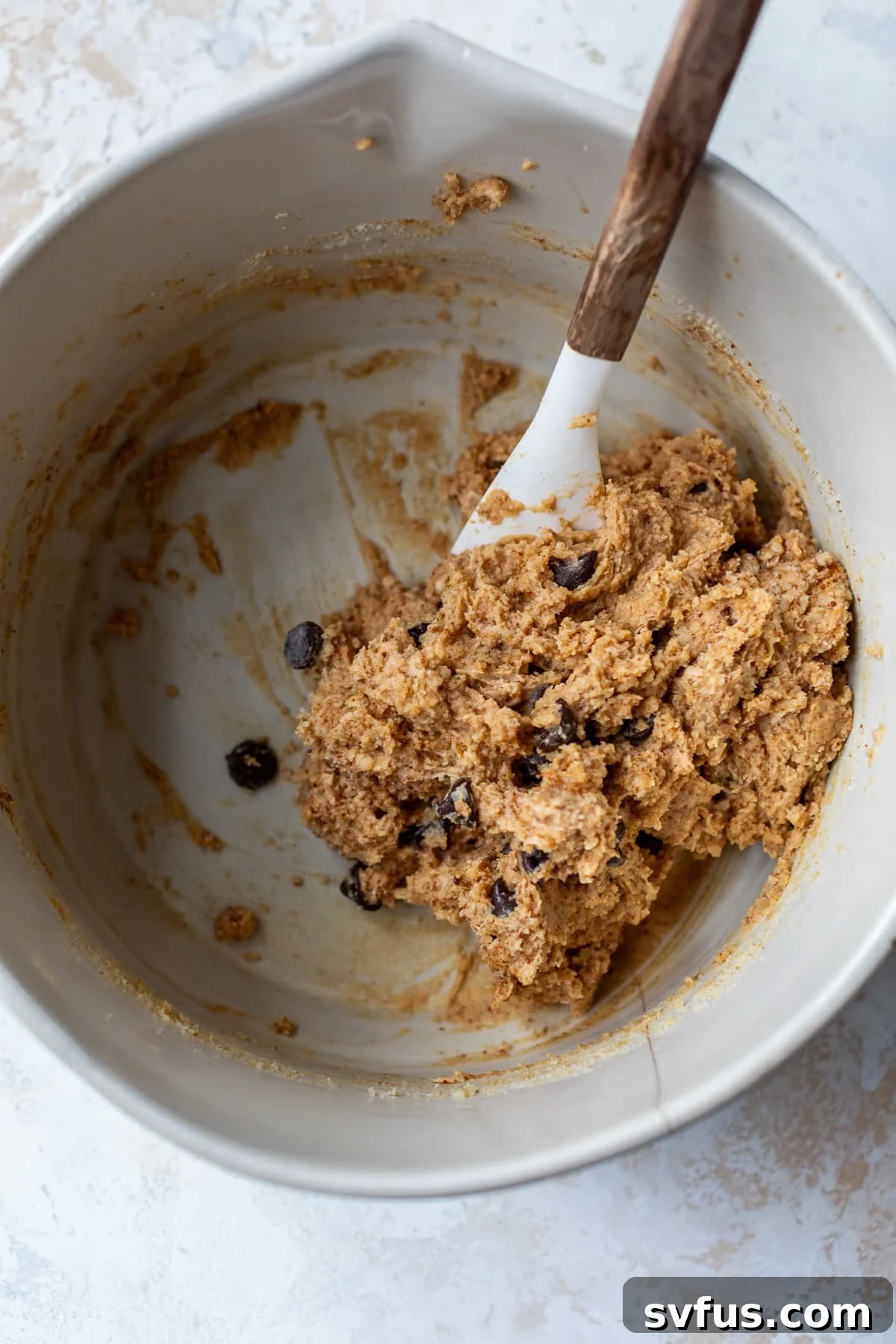 cookie dough in a large bowl with a spatula, ready for shaping