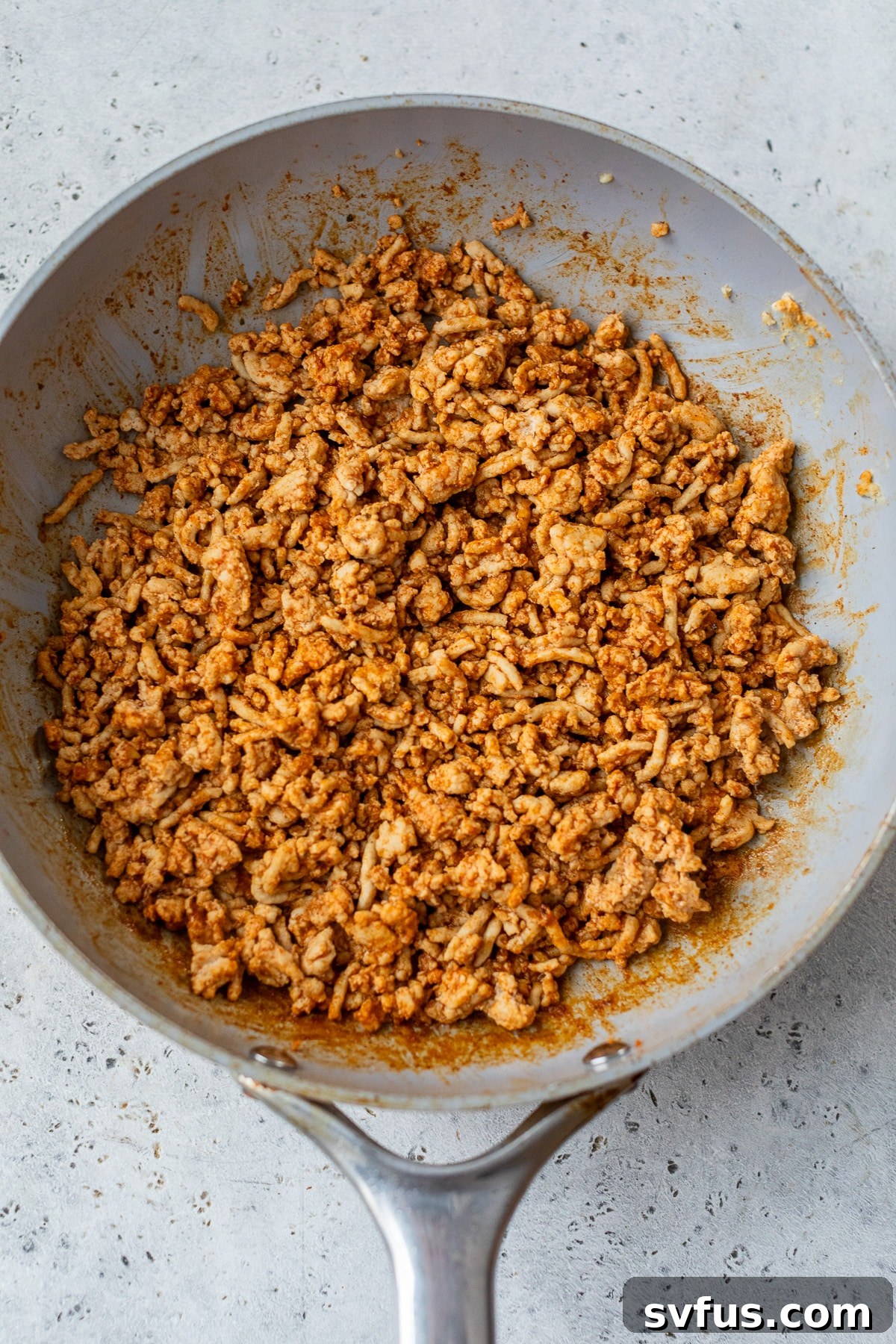 Ground chicken cooking in a skillet with taco seasoning.
